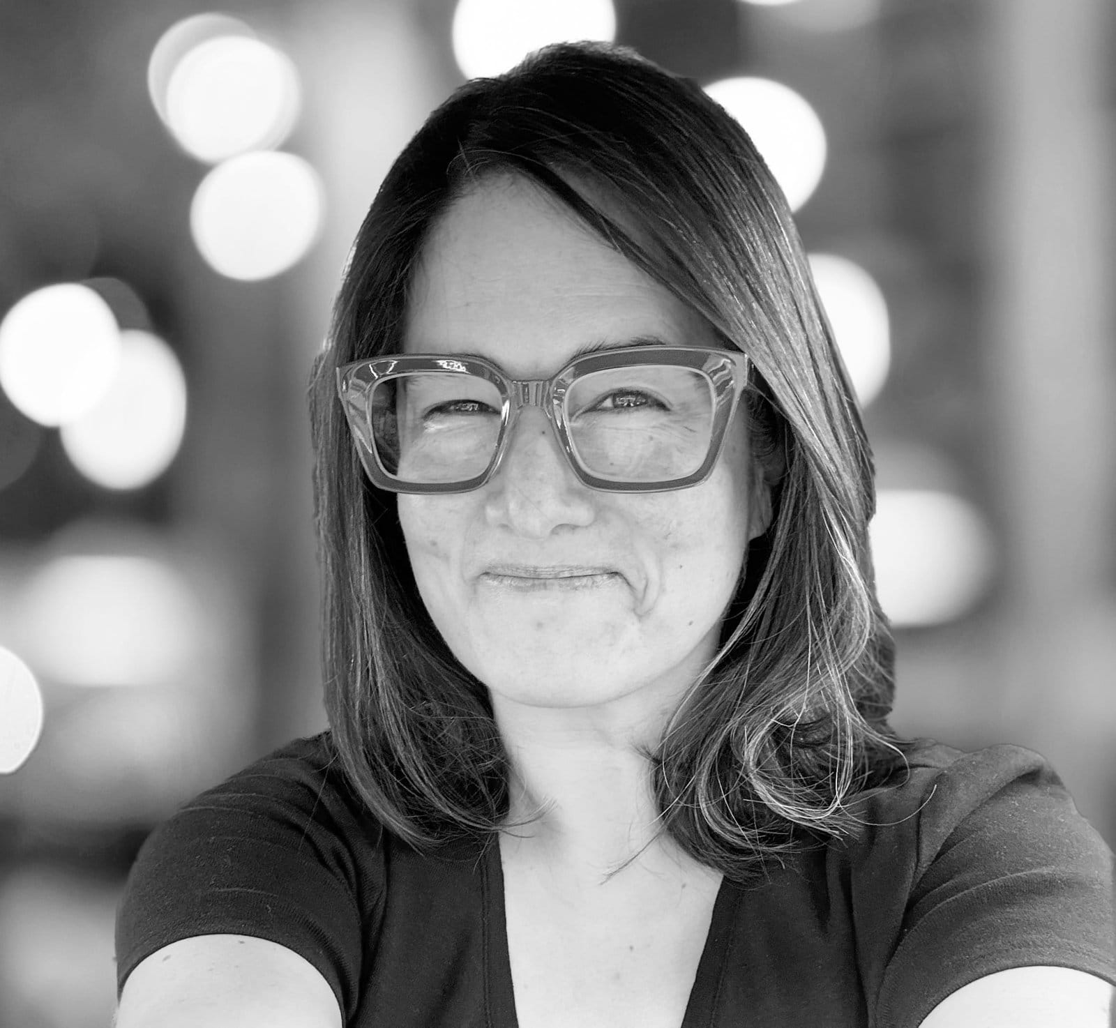 Ruthanne Reid, a middle-aged white woman with shoulder-length brown hair and large glasses, smiling.